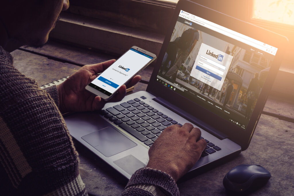 person logging into LinkedIn on their phone and laptop